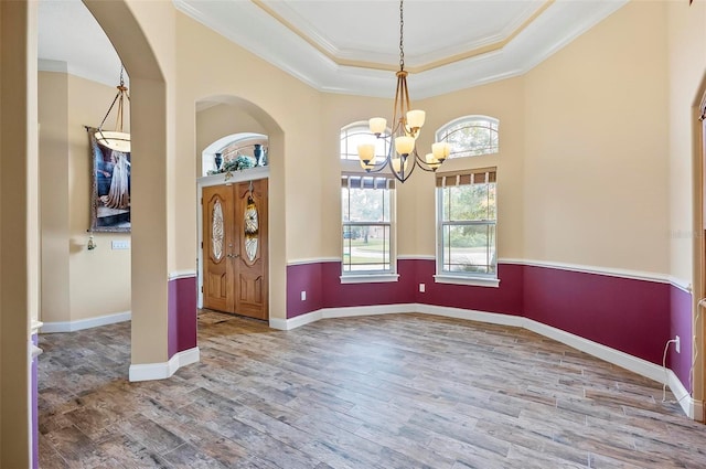 entrance foyer with crown molding, a notable chandelier, wood-type flooring, and a raised ceiling