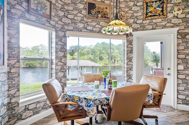 dining area featuring a water view, hardwood / wood-style flooring, and a healthy amount of sunlight