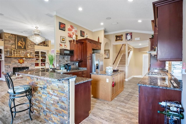 kitchen featuring kitchen peninsula, a kitchen island, a breakfast bar, light hardwood / wood-style flooring, and ornamental molding