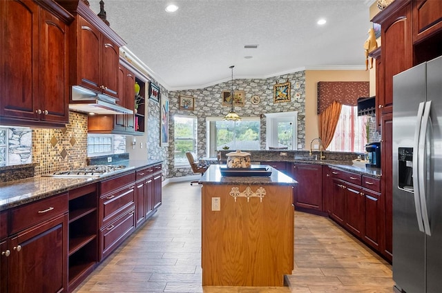 kitchen featuring appliances with stainless steel finishes, a textured ceiling, a wealth of natural light, light hardwood / wood-style flooring, and a center island