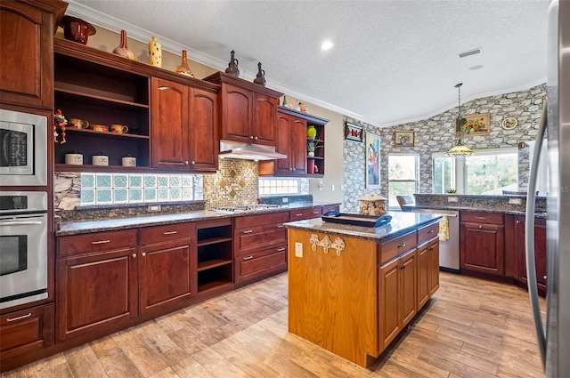 kitchen with lofted ceiling, crown molding, a center island, appliances with stainless steel finishes, and light hardwood / wood-style floors