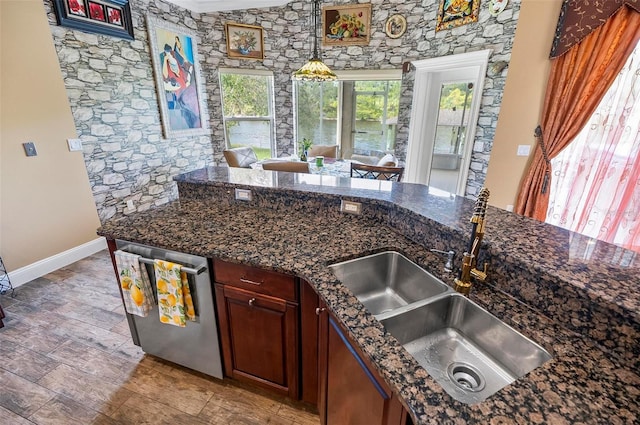 kitchen with hanging light fixtures, dishwasher, dark stone countertops, light hardwood / wood-style floors, and sink