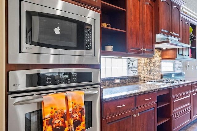 kitchen with dark stone countertops, backsplash, appliances with stainless steel finishes, and a wealth of natural light