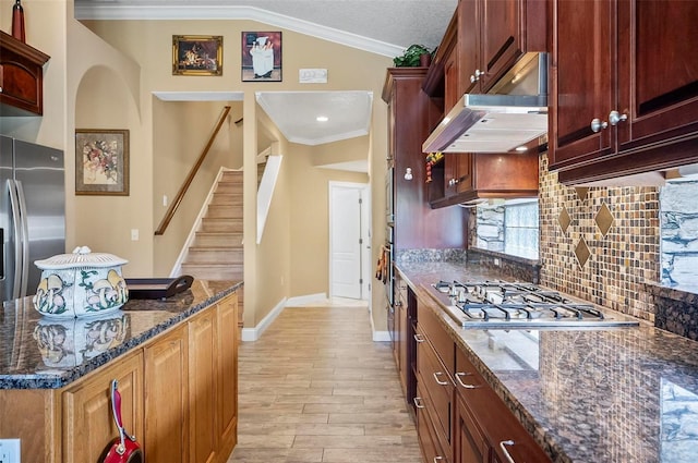 kitchen with lofted ceiling, decorative backsplash, stainless steel appliances, crown molding, and light hardwood / wood-style floors