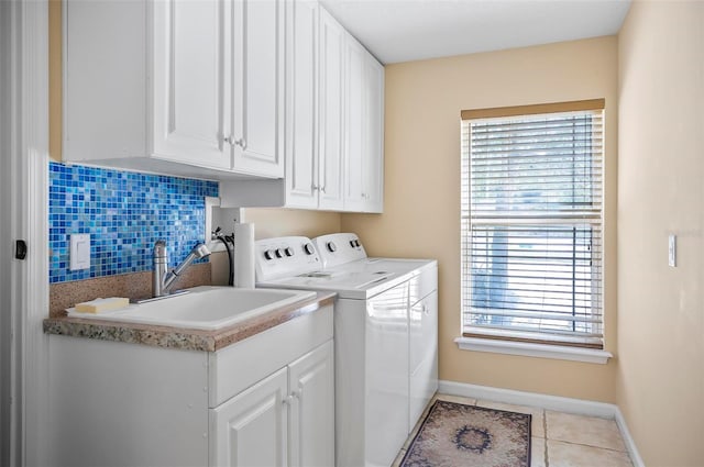 clothes washing area with sink, independent washer and dryer, light tile patterned floors, and cabinets