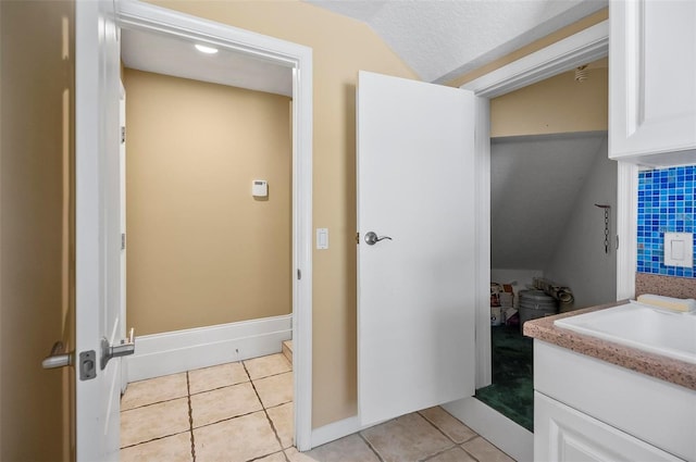 bathroom with vanity, a textured ceiling, lofted ceiling, and tile patterned floors