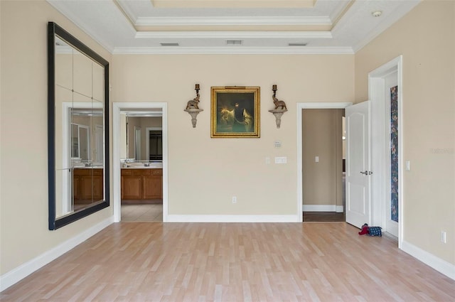 spare room with a tray ceiling, ornamental molding, and light hardwood / wood-style flooring