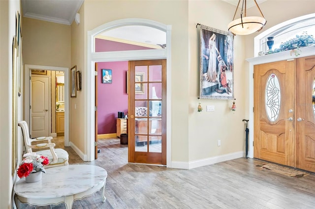 foyer featuring french doors, light hardwood / wood-style floors, crown molding, and plenty of natural light