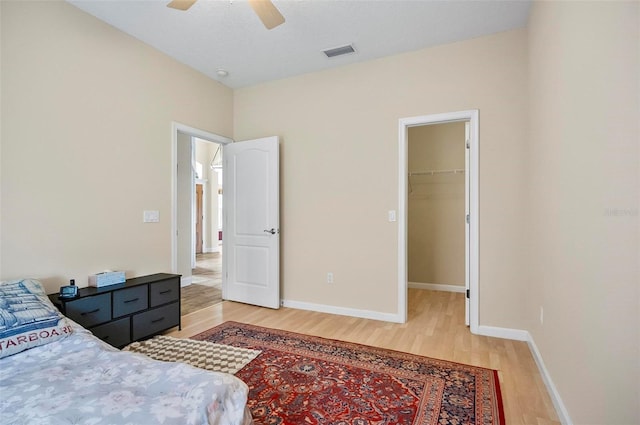 bedroom with hardwood / wood-style floors, a walk in closet, a closet, and ceiling fan