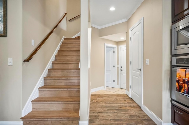 staircase with crown molding and wood-type flooring