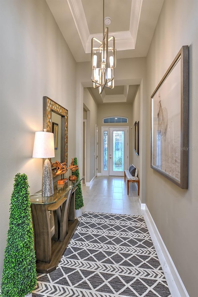 interior space featuring ornamental molding, a notable chandelier, light tile patterned flooring, and a raised ceiling