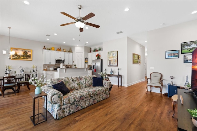 living room featuring dark hardwood / wood-style flooring and ceiling fan with notable chandelier