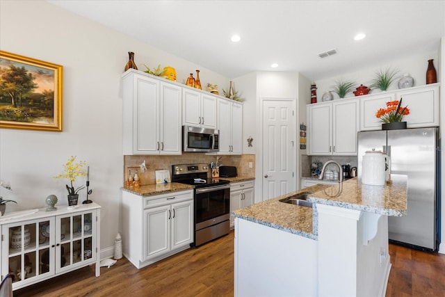 kitchen featuring appliances with stainless steel finishes, sink, dark hardwood / wood-style flooring, white cabinets, and a center island with sink