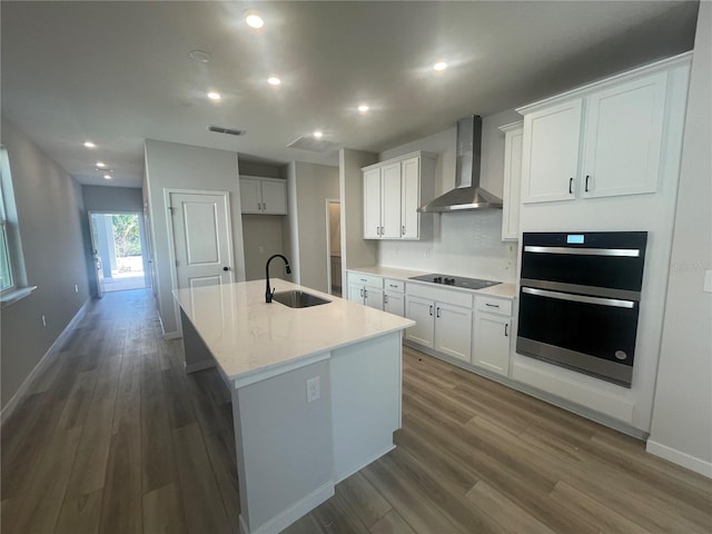 kitchen with black appliances, sink, white cabinets, and wall chimney exhaust hood