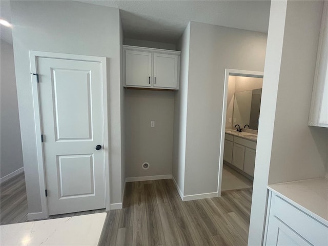 clothes washing area featuring sink and light hardwood / wood-style flooring