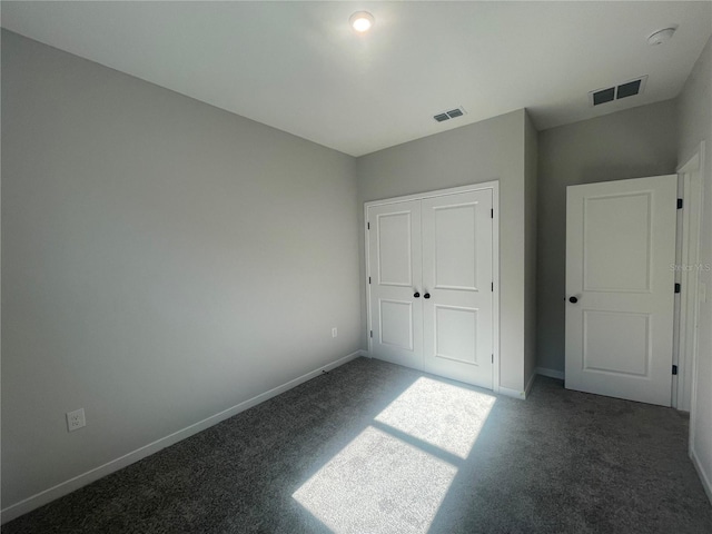 unfurnished bedroom featuring dark carpet and a closet