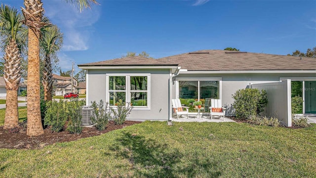 rear view of house with cooling unit, a patio area, and a lawn