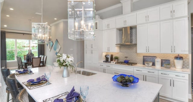 kitchen with white cabinetry, ornamental molding, stainless steel gas cooktop, wall chimney exhaust hood, and sink