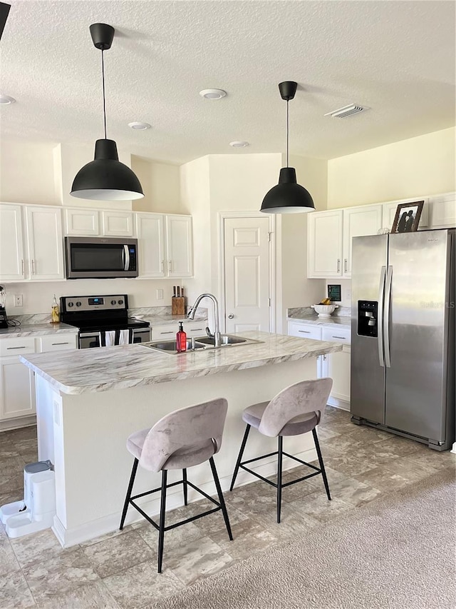 kitchen with sink, a kitchen breakfast bar, white cabinetry, stainless steel appliances, and a kitchen island with sink