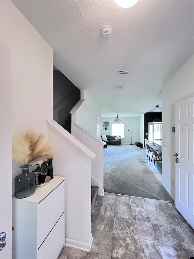 hallway with a textured ceiling and carpet floors