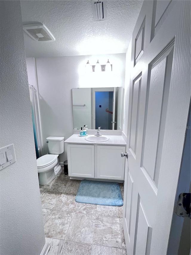 bathroom featuring vanity, toilet, and a textured ceiling