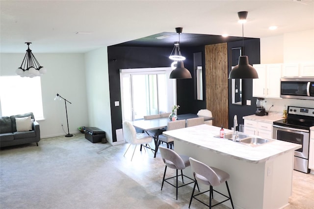 kitchen featuring white cabinets, a kitchen island with sink, sink, pendant lighting, and stainless steel appliances