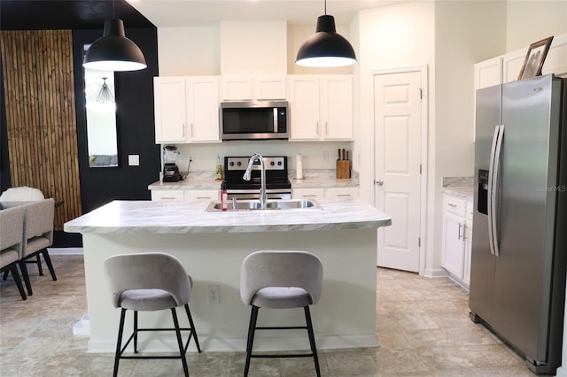 kitchen featuring stainless steel appliances, hanging light fixtures, and an island with sink