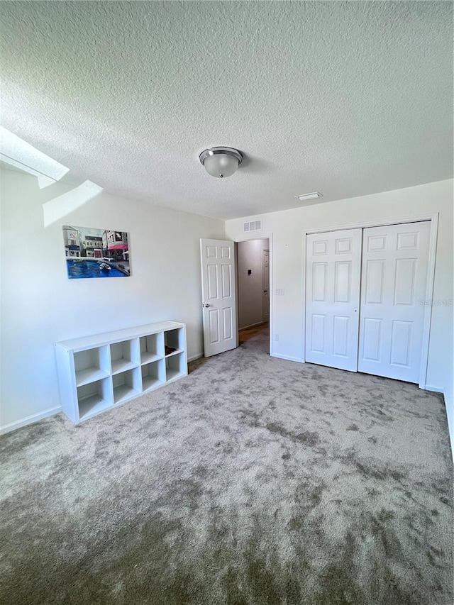 unfurnished bedroom with a textured ceiling, carpet flooring, and a closet