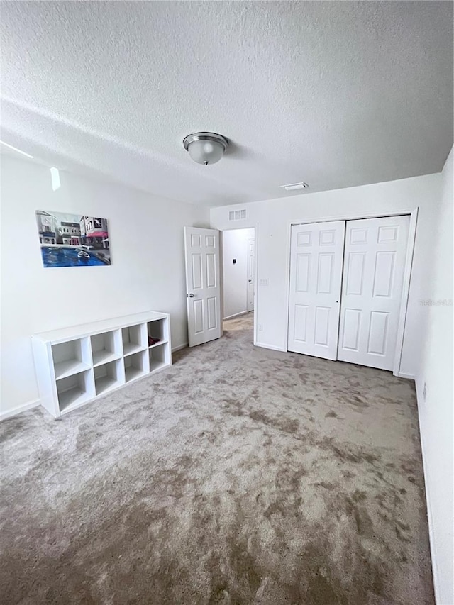 unfurnished bedroom with a textured ceiling, carpet flooring, and a closet