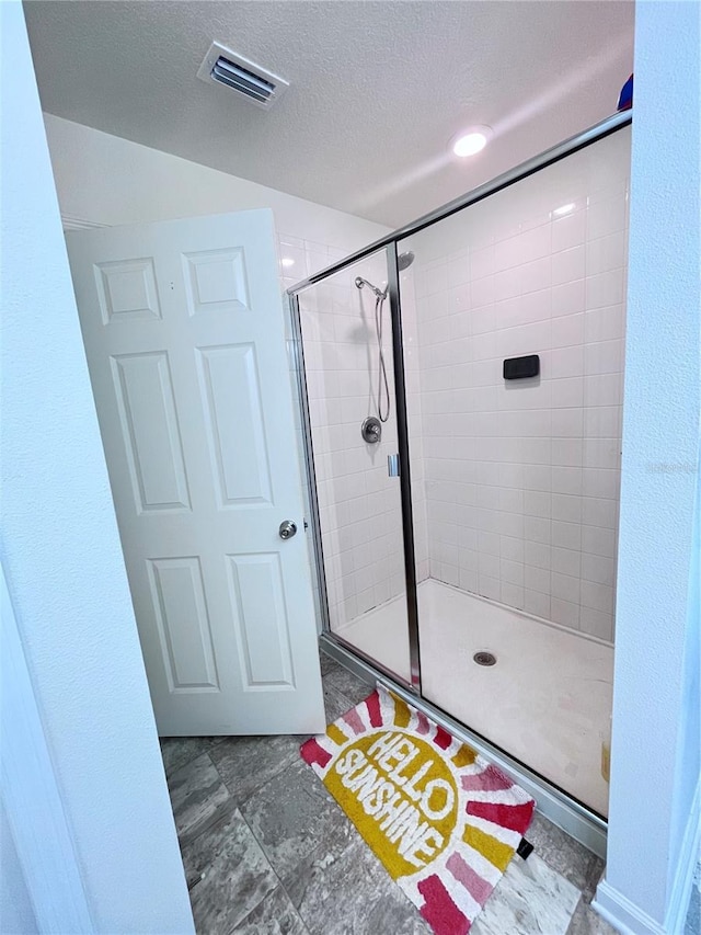 bathroom with a textured ceiling and a shower with shower door