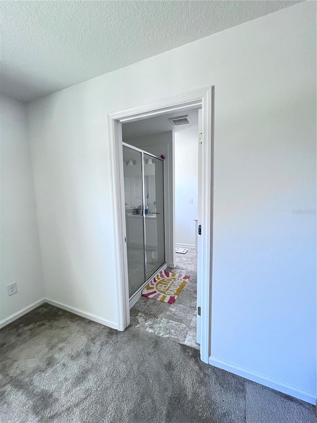 spare room with a textured ceiling and dark carpet