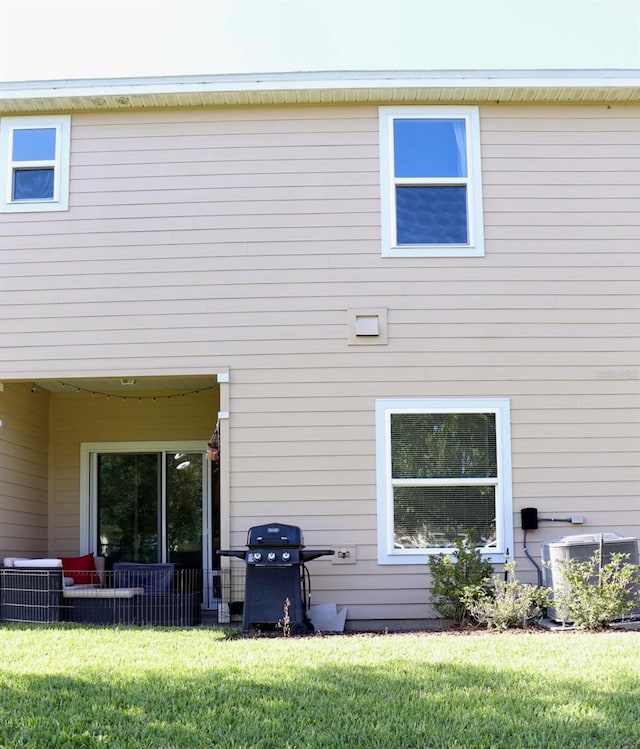 rear view of property with central air condition unit and a lawn