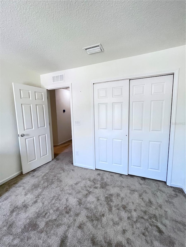 unfurnished bedroom with a closet, a textured ceiling, and carpet