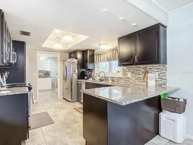 kitchen with kitchen peninsula, light stone countertops, decorative light fixtures, and stainless steel refrigerator