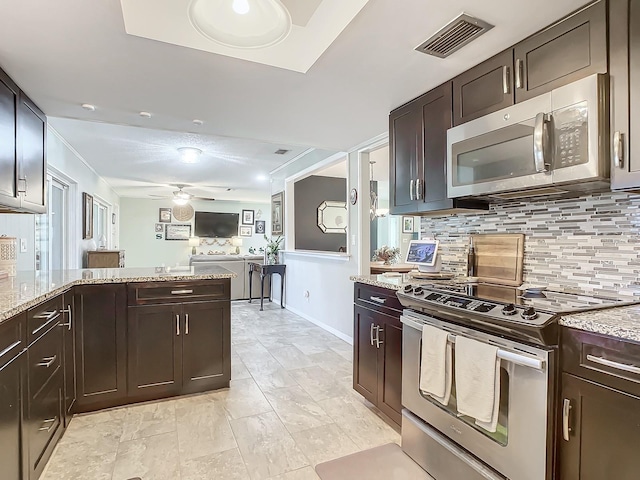 kitchen with light stone countertops, appliances with stainless steel finishes, backsplash, visible vents, and a ceiling fan