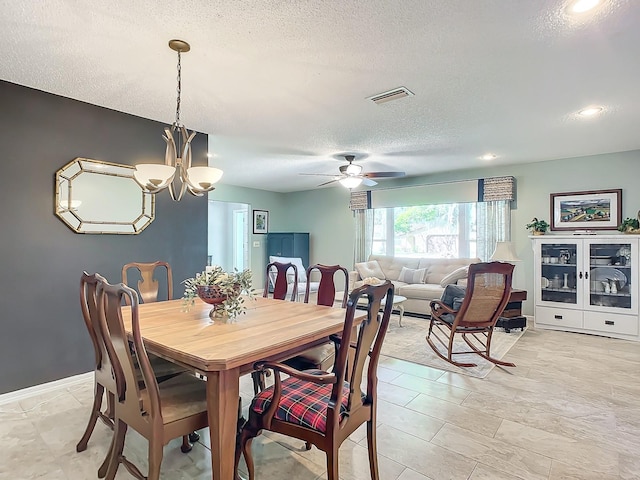 dining space featuring a textured ceiling and ceiling fan with notable chandelier