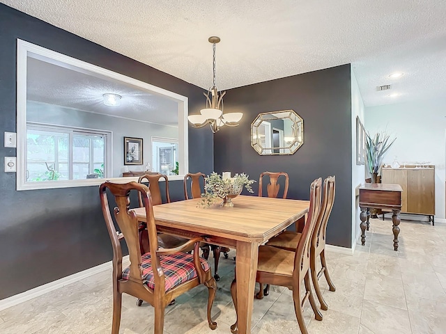 dining area with a textured ceiling, visible vents, a chandelier, and baseboards