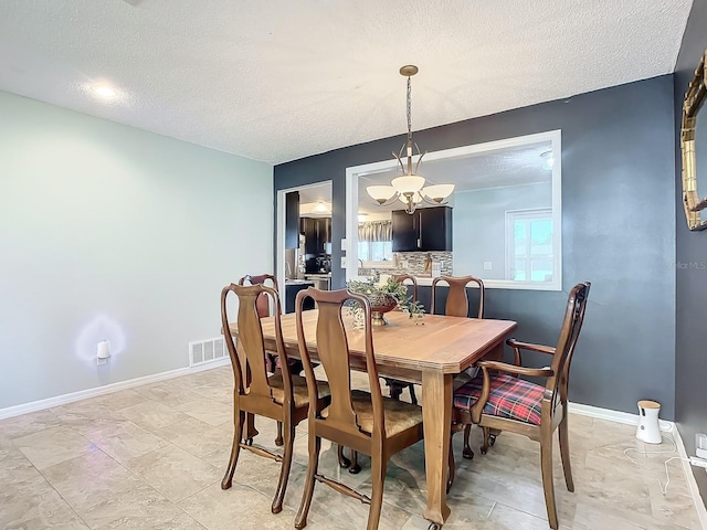 dining room with an inviting chandelier and a textured ceiling