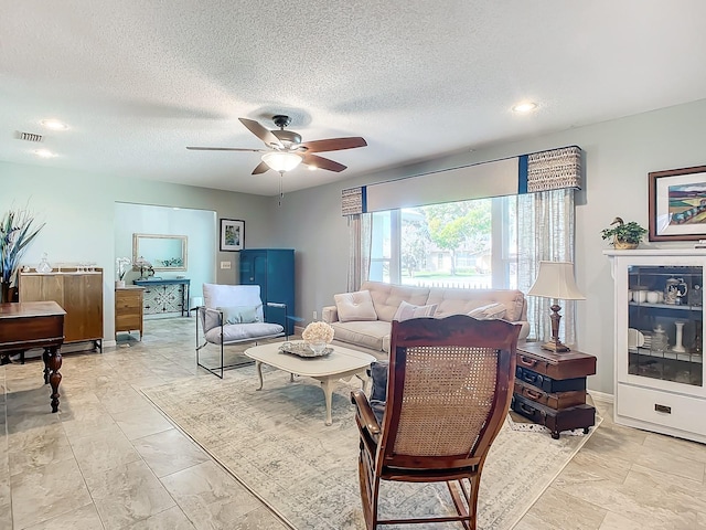 living room featuring ceiling fan and a textured ceiling