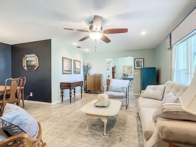 living room featuring ceiling fan and a textured ceiling