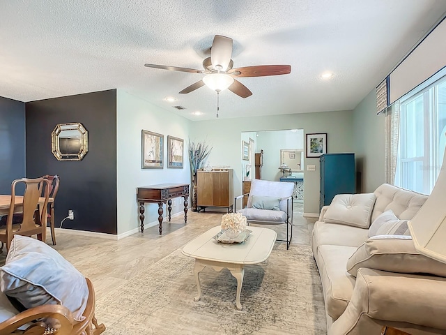 living room with recessed lighting, baseboards, visible vents, a ceiling fan, and a textured ceiling