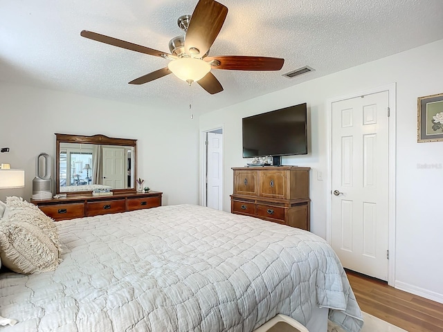 bedroom featuring hardwood / wood-style floors, a textured ceiling, and ceiling fan