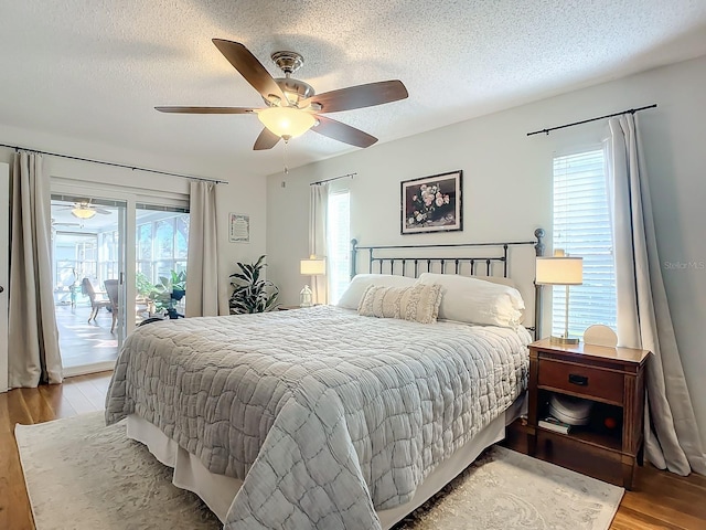 bedroom featuring ceiling fan, multiple windows, hardwood / wood-style floors, and access to exterior