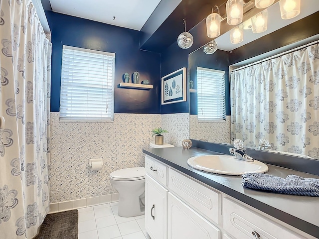 bathroom with tile walls, vanity, tile patterned floors, toilet, and wainscoting