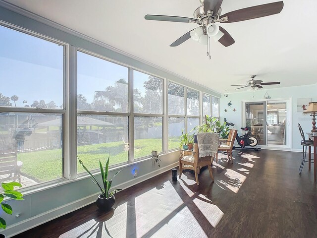 sunroom / solarium with ceiling fan, wood finished floors, and baseboards