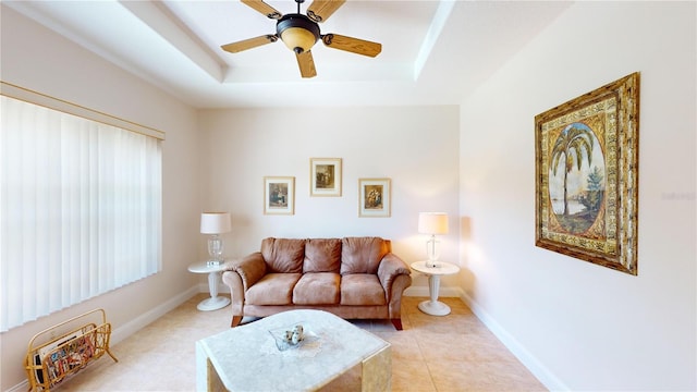 tiled living room with ceiling fan and a raised ceiling