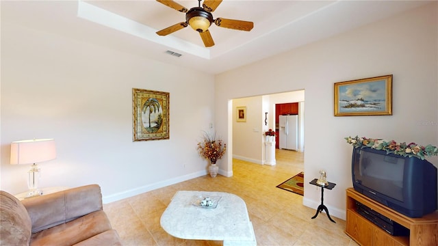 living room featuring light tile patterned floors, a raised ceiling, and ceiling fan