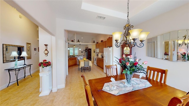 dining area with a notable chandelier, a tray ceiling, and light tile patterned floors