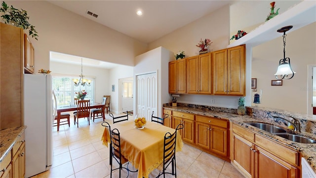 kitchen with white fridge, sink, hanging light fixtures, and light tile patterned floors