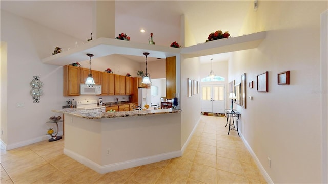 kitchen featuring kitchen peninsula, hanging light fixtures, light tile patterned floors, light stone countertops, and white appliances